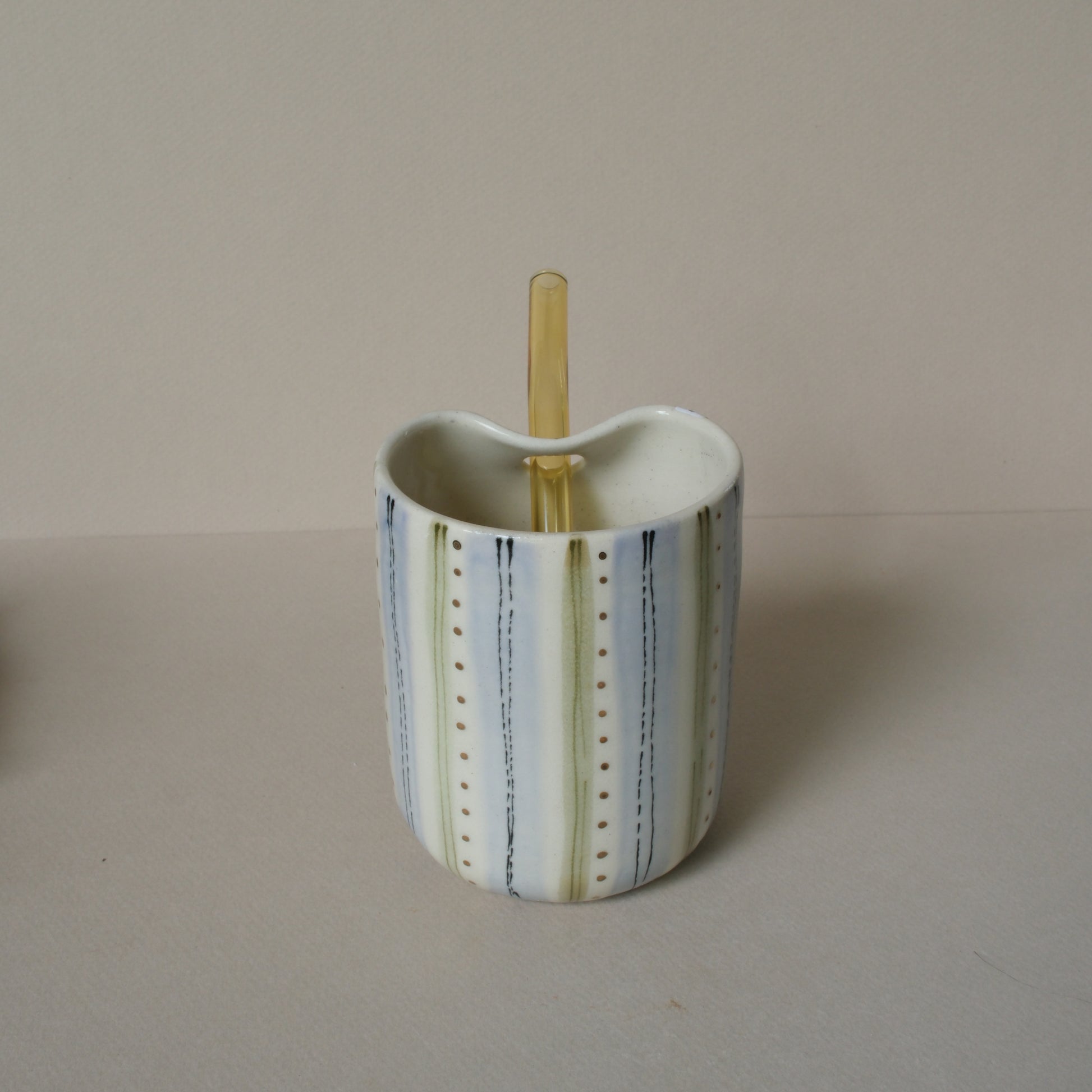 Ceramic cup with a straw on a beige background