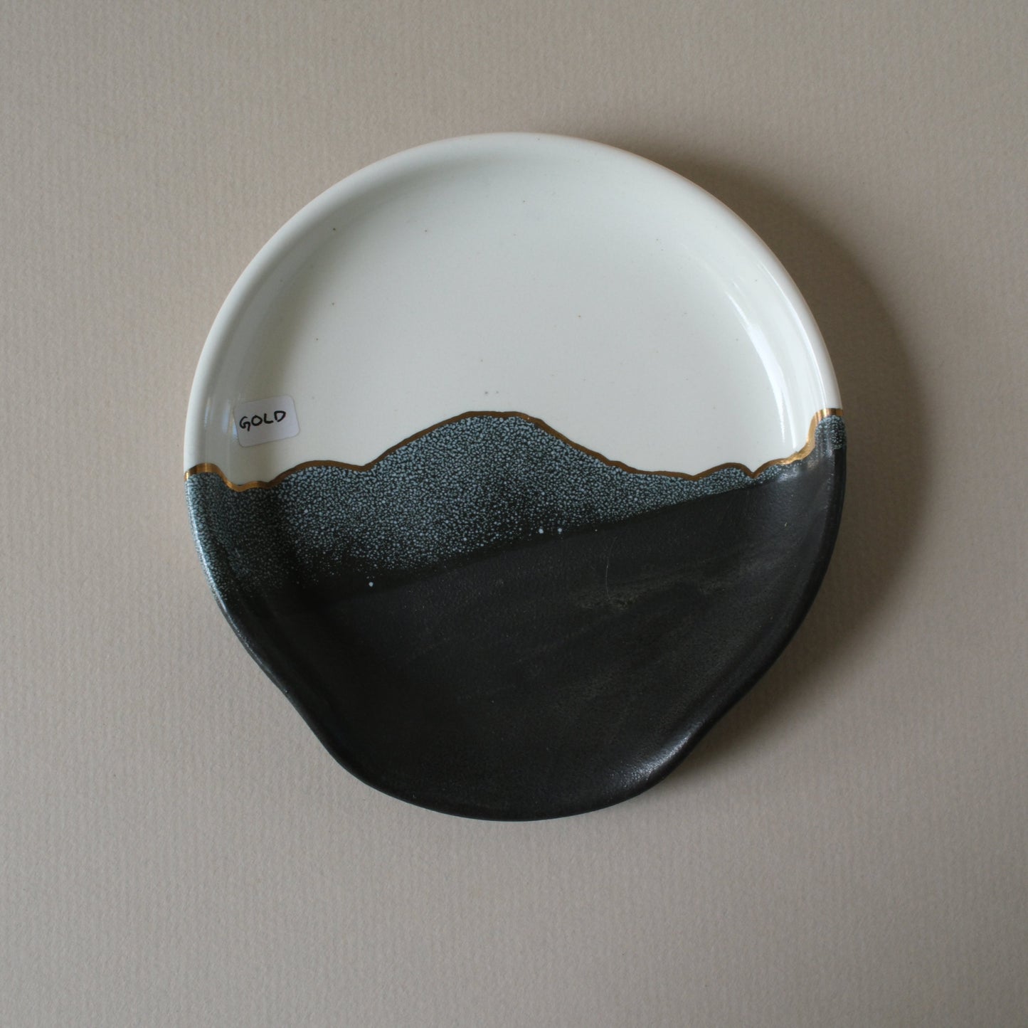 Ceramic plate with black and white design with gold detailing on a stoneware