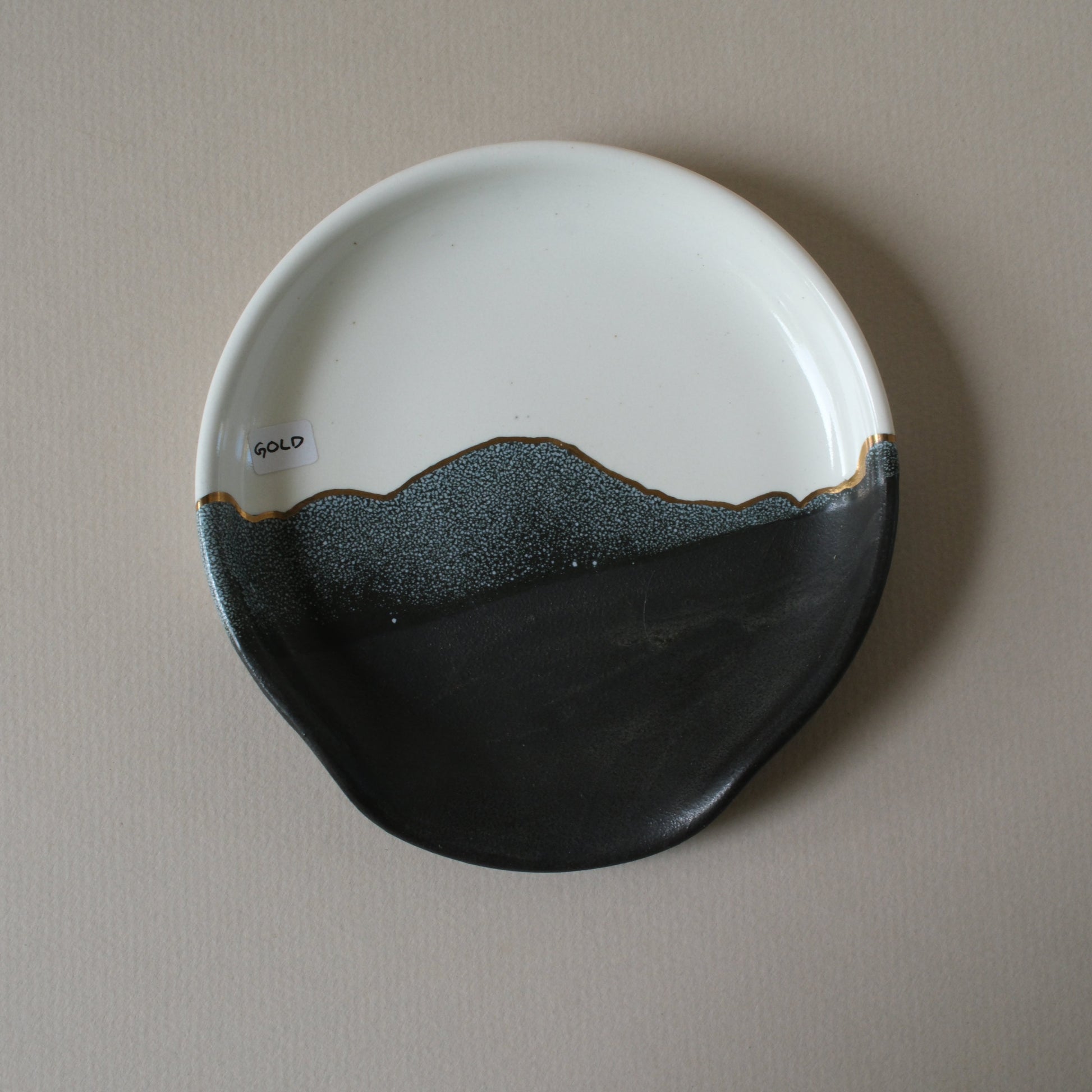 Ceramic plate with black and white design with gold detailing on a stoneware