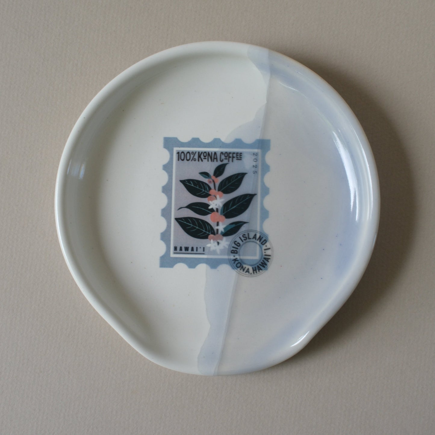 White ceramic plate with a decorative Kona Coffee stamp design