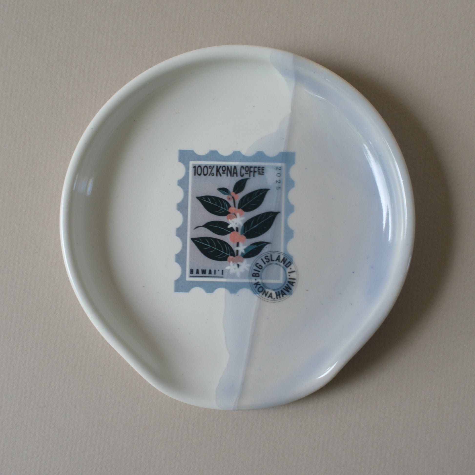 White ceramic plate with a decorative Kona Coffee stamp design